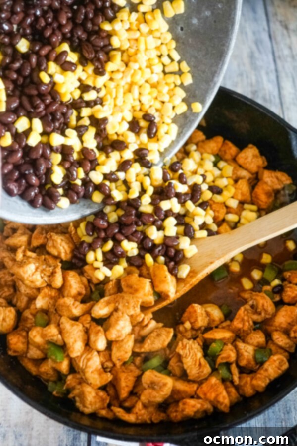 Black beans and corn being poured from a colander into the skillet, ready to be mixed with the chicken and vegetables.