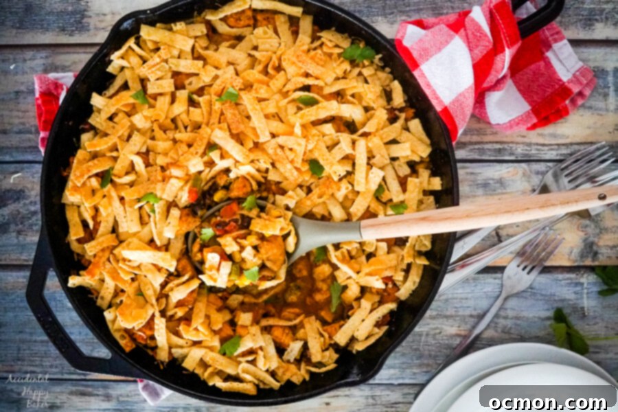Crispy wonton strips are carefully added to the top of the Southwestern Chicken Egg Roll Casserole, layered over melted cheese.