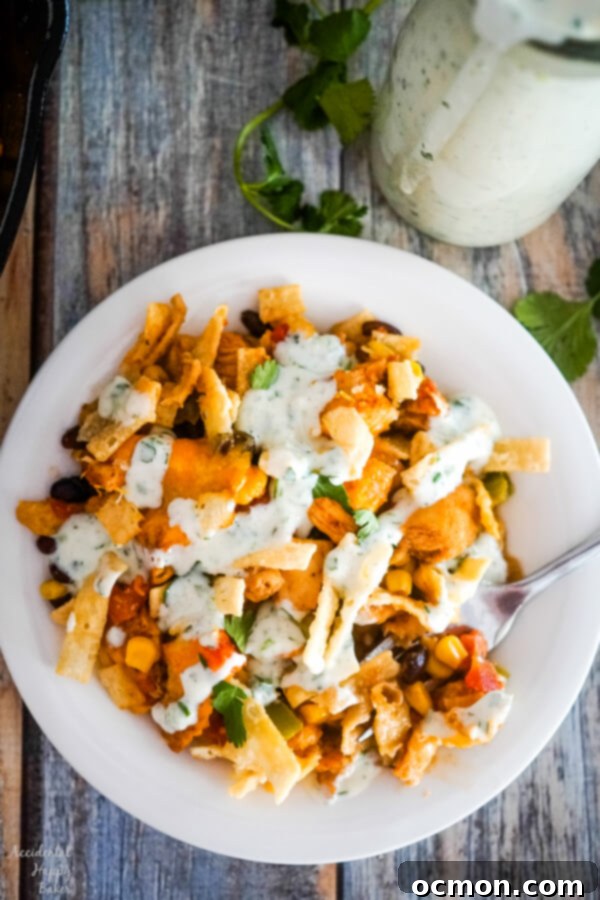 A serving of Southwestern Egg Roll Bake presented on a white plate, beautifully drizzled with creamy Cilantro Jalapeno Ranch dressing.