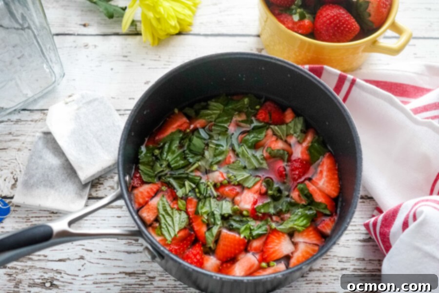 Crimson Basil Cooler 3 Freshly sliced strawberries and aromatic basil leaves in a saucepan, ready for syrup infusion for homemade iced tea.