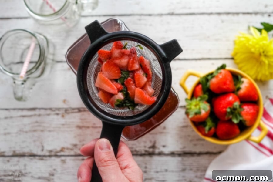 Crimson Basil Cooler 4 Straining the cooked strawberry and basil mixture to create a smooth, flavorful syrup for iced tea.