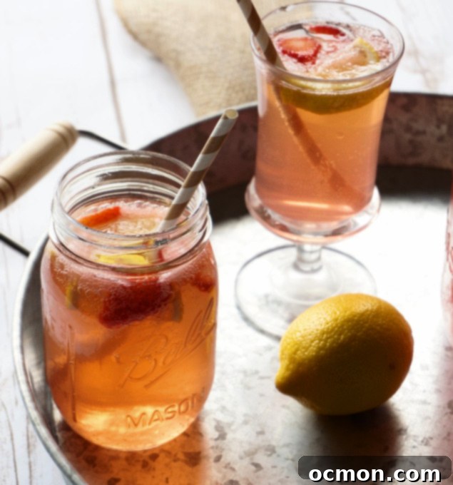 Crimson Basil Cooler 6 A glass of Strawberry Lemonade Shandy with a lemon slice and a strawberry garnish.