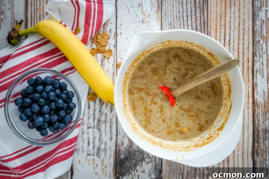Wholesome Blueberry Bran Muffins 4 A medium mixing bowl with bran flakes soaking in hot water and milk, appearing soft and hydrated.