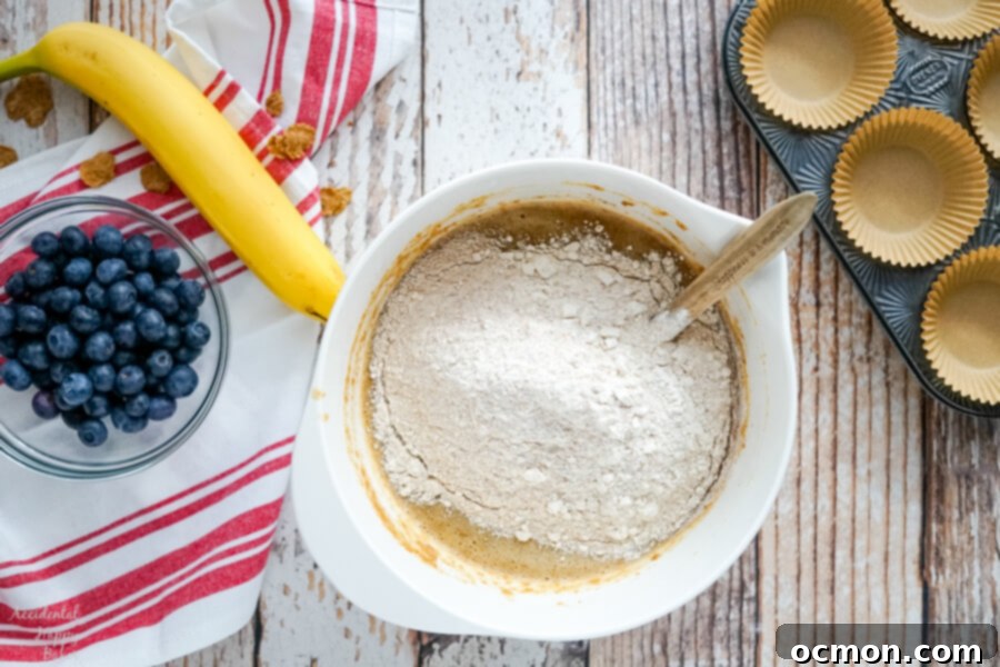 Wholesome Blueberry Bran Muffins 5 The dry ingredients, including all-purpose and whole wheat flour, baking powder, baking soda, and salt, are carefully added to the wet bran mixture in a single bowl.