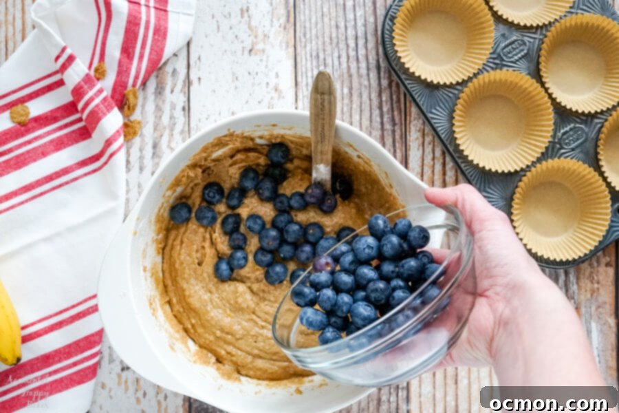 Wholesome Blueberry Bran Muffins 6 Plump fresh blueberries being gently folded into the muffin batter, ready for baking.