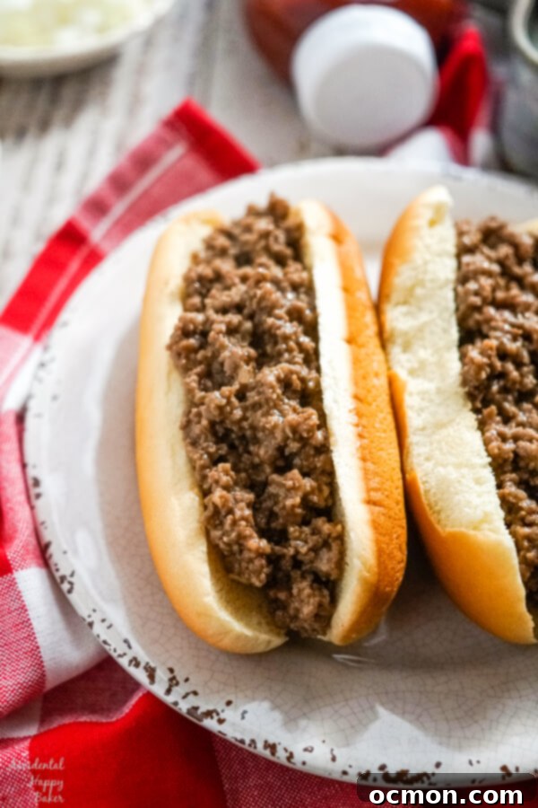 Two freshly made loose meat sandwiches on a pristine white plate, showcasing the flavorful beef filling.
