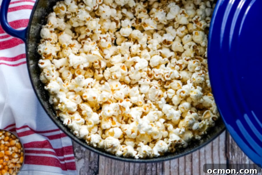 A blue dutch oven full of freshly popped popcorn.