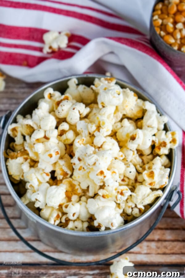A serving bowl of popcorn next to a red and white striped towel.