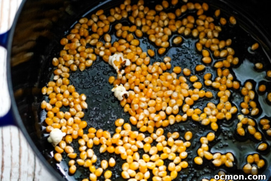A blue dutch oven full of popcorn ready to be popped.