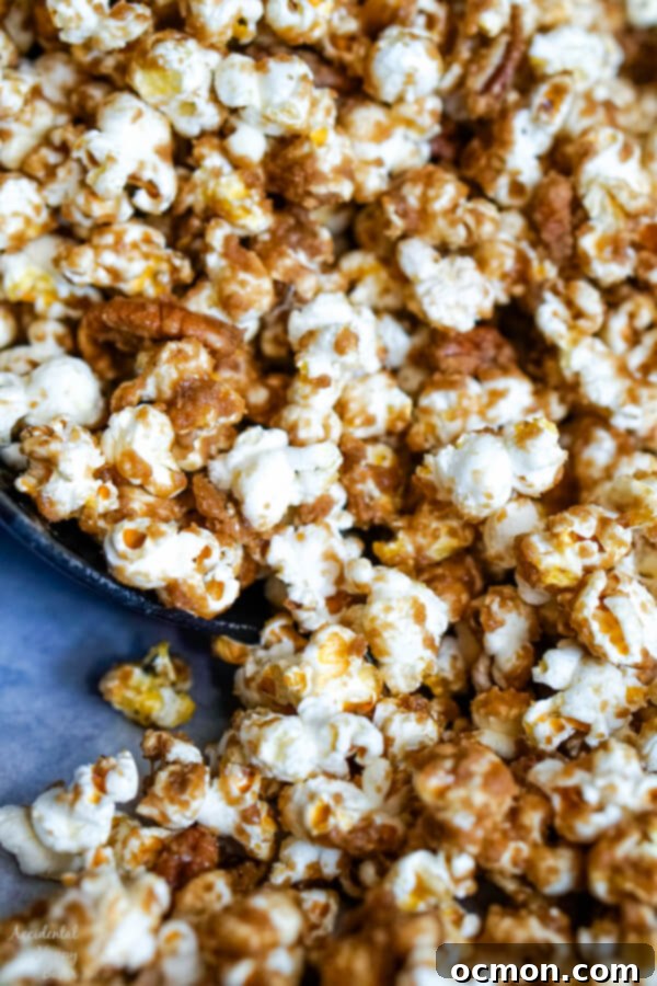 A close up image of the popcorn that shows the texture of the caramel on the popcorn and pecans. 
