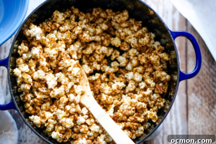 A blue dutch oven of caramel corn with a wooden spoon. 