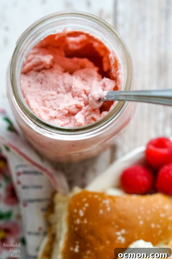 Whipped Raspberry Honey Butter 7 A close-up shot of a mason jar filled with the finished, vibrant raspberry honey butter, showing its smooth, creamy consistency with flecks of raspberry.