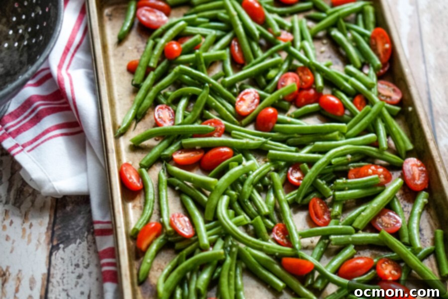 Savory Green Bean and Tomato Bake 3 Green beans and tomatoes drizzled with olive oil and garlic on a sheet pan.