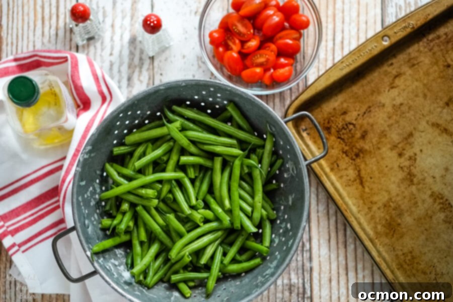 Savory Green Bean and Tomato Bake 4 Green beans in a metal colander, next to a bowl of tomatoes, olive oil, salt and pepper.