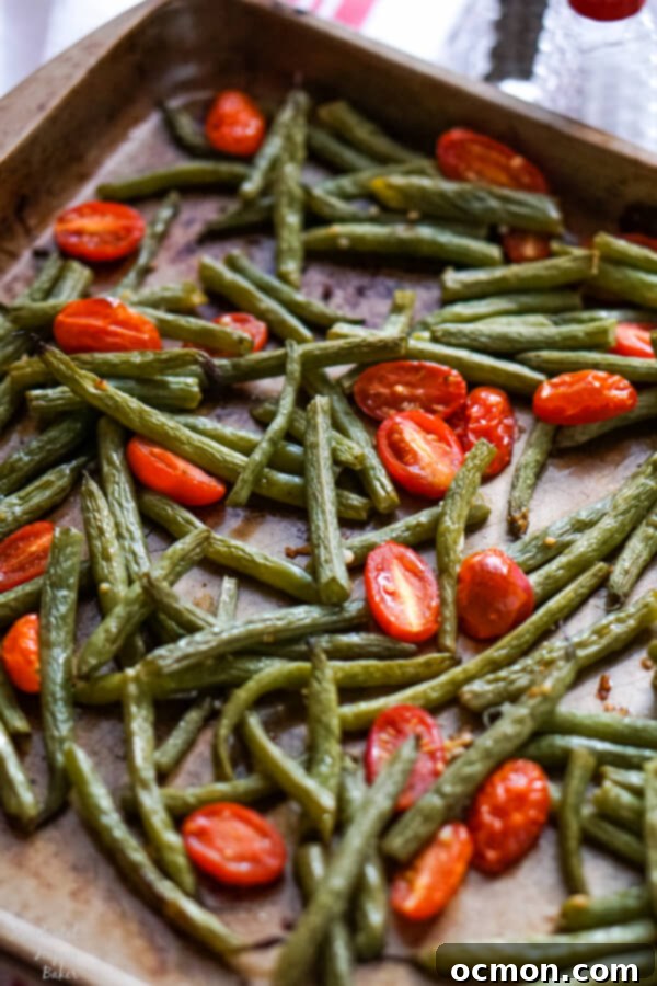 Savory Green Bean and Tomato Bake 6 Green beans and cherry tomatoes on a sheet pan just after coming out of the oven.