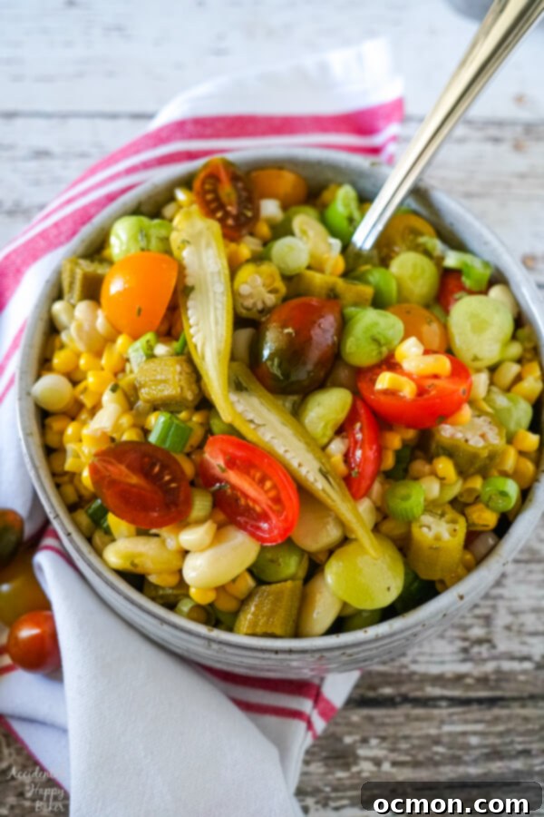 A vibrant bowl of Succotash Salad, showcasing colorful corn, lima beans, and cherry tomatoes, topped with sliced pickled okra.
