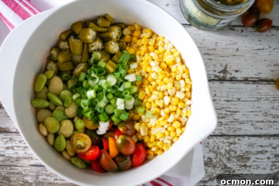 Ingredients for Succotash Salad laid out on a cutting board, including corn, lima beans, tomatoes, and scallions.