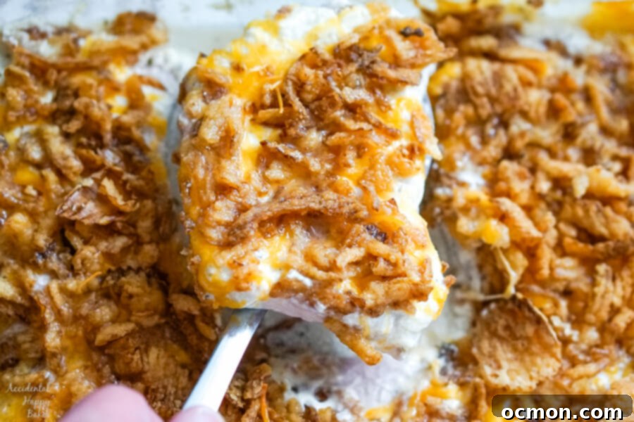 A closeup image of a pork chop being served, showcasing its creamy sauce and crispy onion topping.
