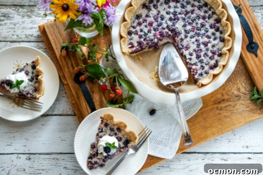 Luscious Blackberry Cream Pie 7 Finished blackberries and cream pie, served with fresh whipped cream and mint, with a spoonful removed to show the creamy filling.