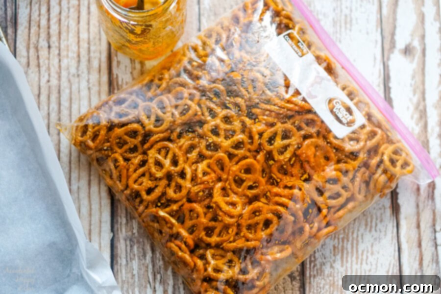 A sealed Ziploc bag filled with pretzels evenly coated in the orange-red spicy sriracha ranch seasoning, ready for baking.