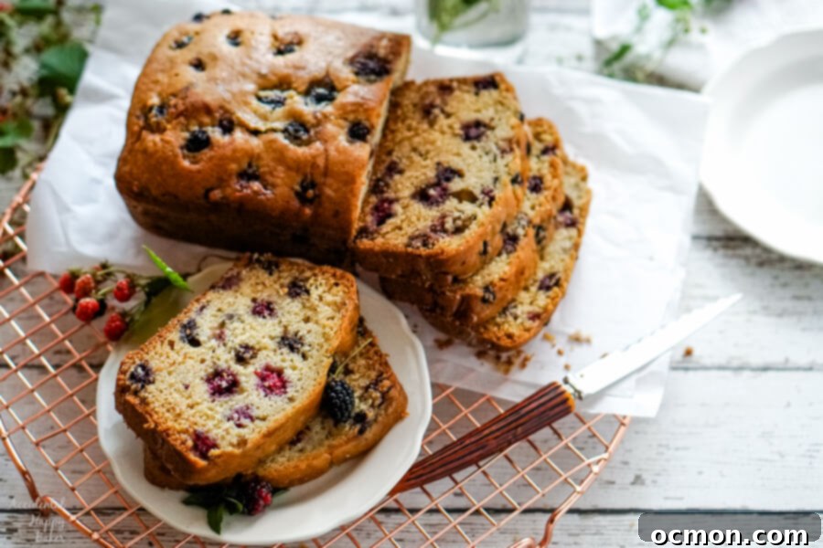 Blackberry Bliss Loaf 2 Two slices of blackberry bread on a white plate next to a loaf of sliced blackberry bread, highlighting its moist texture and berry distribution.