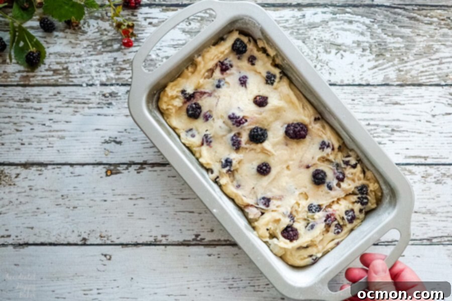 Blackberry Bliss Loaf 4 A silver loaf pan filled with blackberry bread batter, ready for baking, showcasing the berries nestled within the mixture.