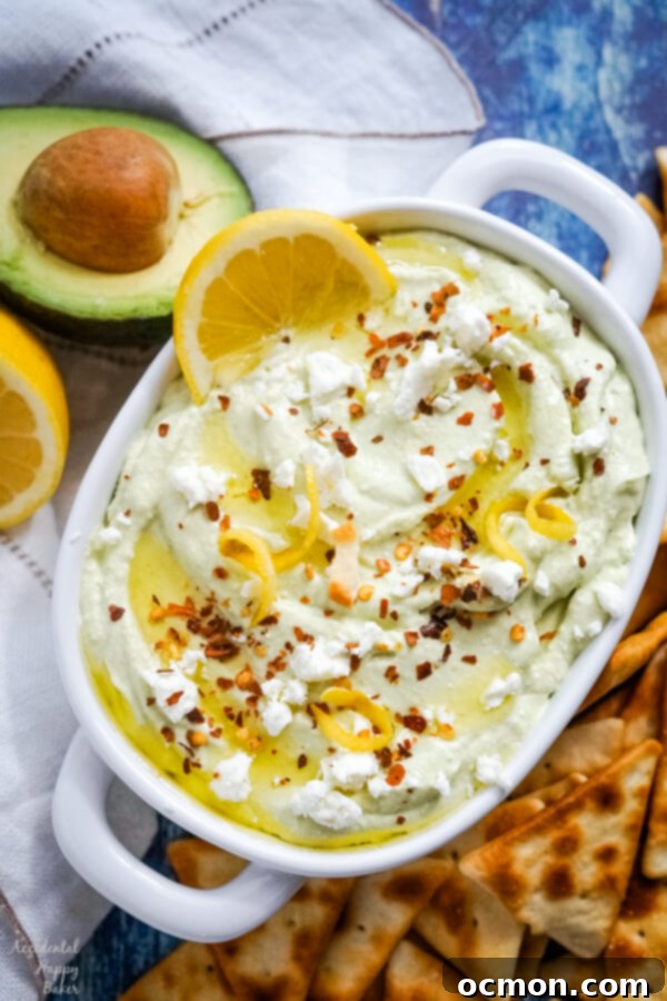 Bright Lemon Feta Dip 2 A white bowl full of lemon feta dip surrounded by pita chips and garnished with sliced lemons.