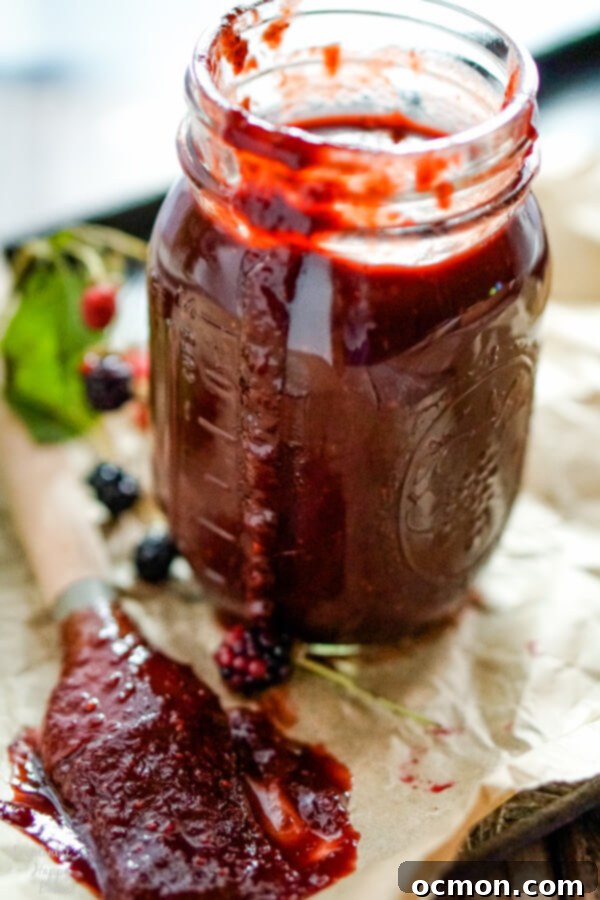 A jar of blackberry bbq sauce with a basting brush to one side. 