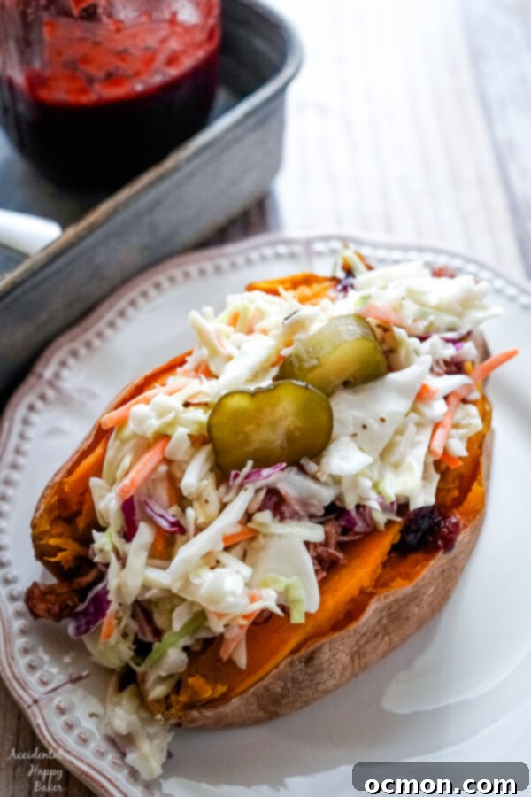 A baked sweet potato stuffed with bbq chicken and coleslaw on a white plate. 