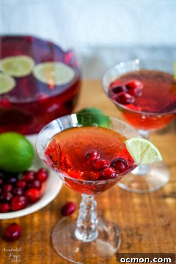 Sparkling Cranberry Moscato Punch 2 A glass of cranberry moscato punch on a wooden serving tray, garnished with fresh cranberries and a lime wedge.