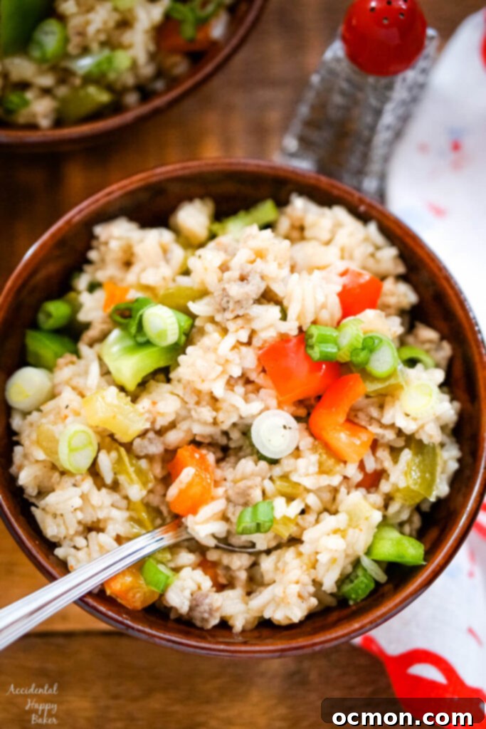 A brown bowl full of dirty rice with sausage on a wooden tray. 