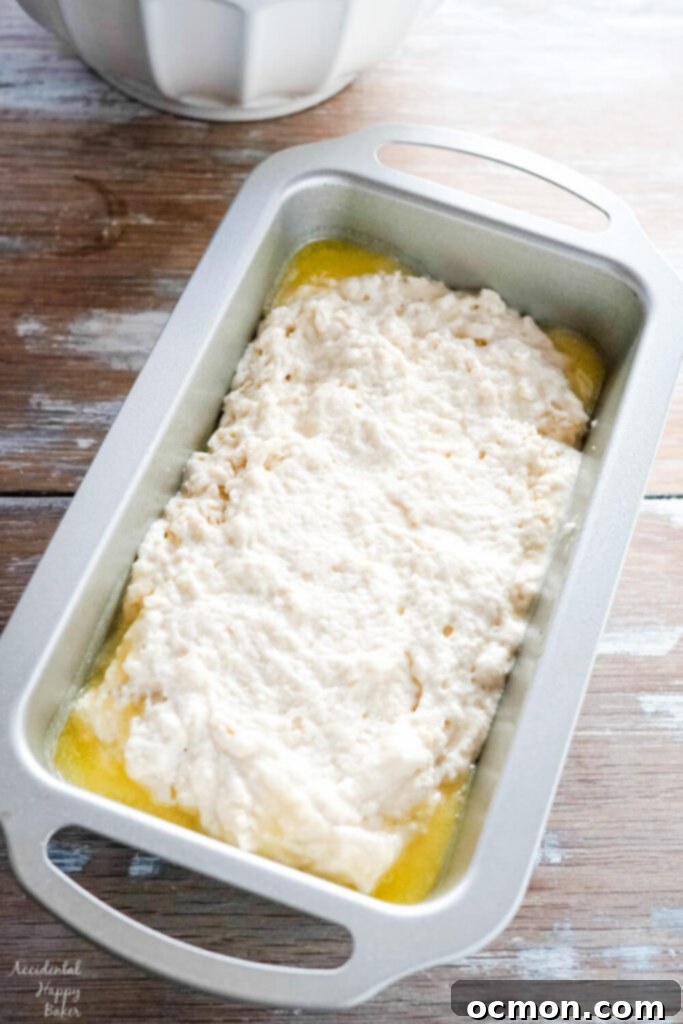Golden Nectar Loaf 6 The prepared honey beer bread batter is carefully spread into a greased loaf pan, its surface ready for the oven to transform it into a golden, crusty loaf.