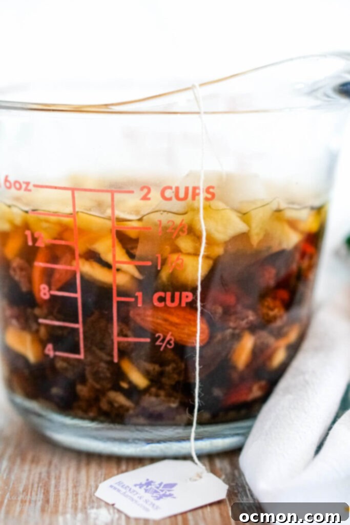 Welsh Bara Brith Tea Bread 6 Dried fruit and a tea bag steeping in boiling water in a measuring cup, preparing for Bara Brith.