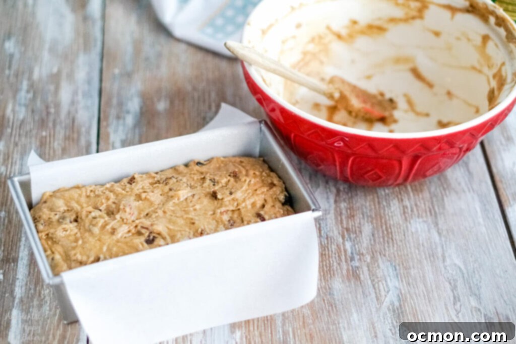 Welsh Bara Brith Tea Bread 8 Bara Brith bread batter being spread evenly into a parchment paper-lined loaf pan before baking.