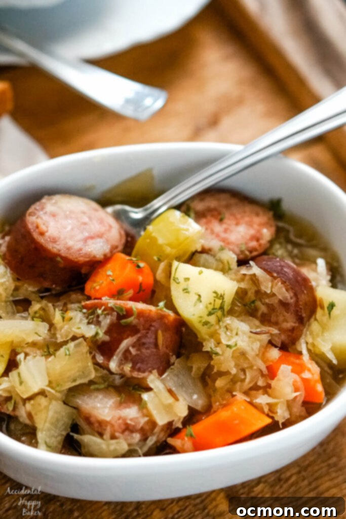 A white bowl of slow cooker kielbasa and sauerkraut on a wooden tray, ready to be served.