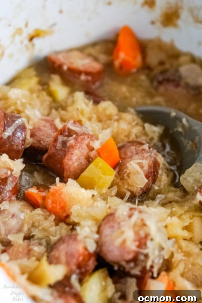 A close up image of the finished kielbasa and sauerkraut, showcasing the tender sausage, kraut, and colorful vegetables after slow cooking.