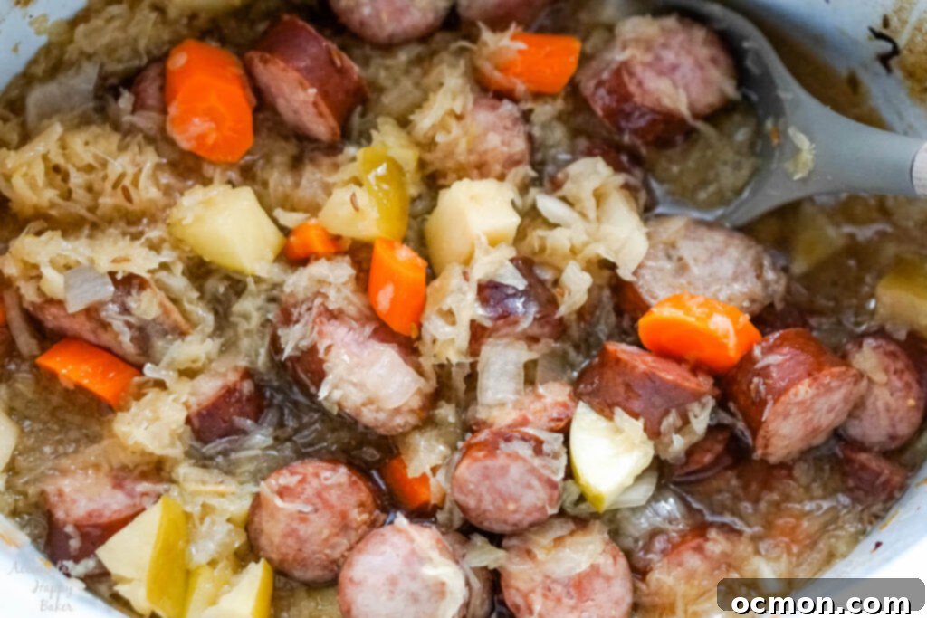 A crockpot filled with perfectly cooked kielbasa and sauerkraut, ready to be served, showing tender meat and vegetables.