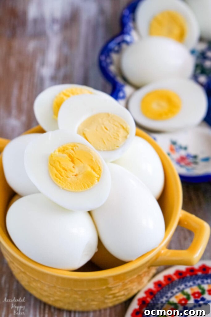 A yellow bowl full of perfectly hard-boiled eggs, with a few sliced eggs displaying creamy yolks.