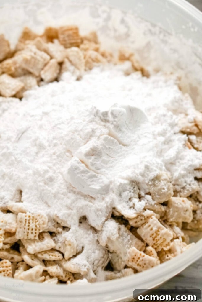 Almond bark covered cereal with powdered sugar and banana pudding mix in a bowl. 