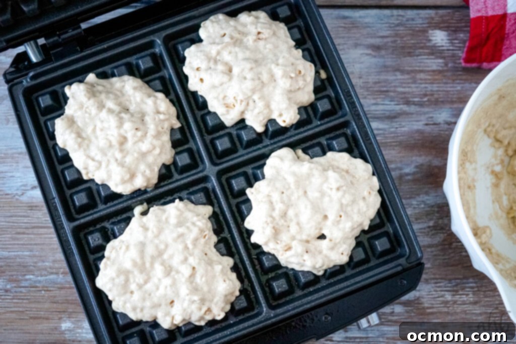 Pouring oatmeal waffle batter into a preheated waffle maker.