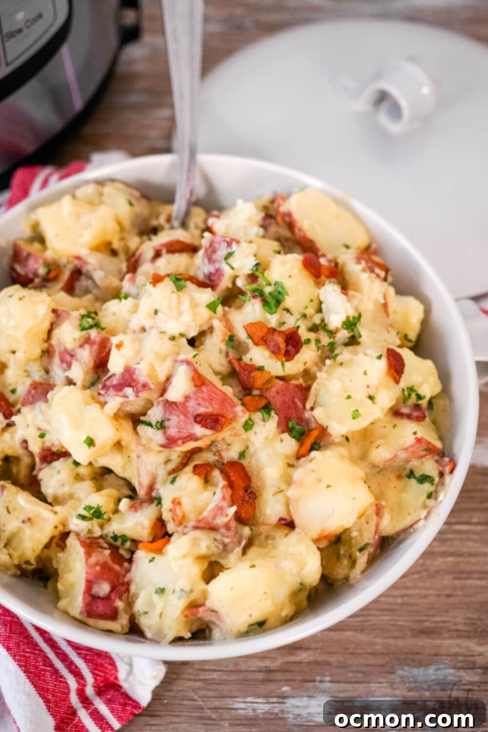 A bowl of creamy ranch potatoes, garnished with fresh parsley and bacon bits.