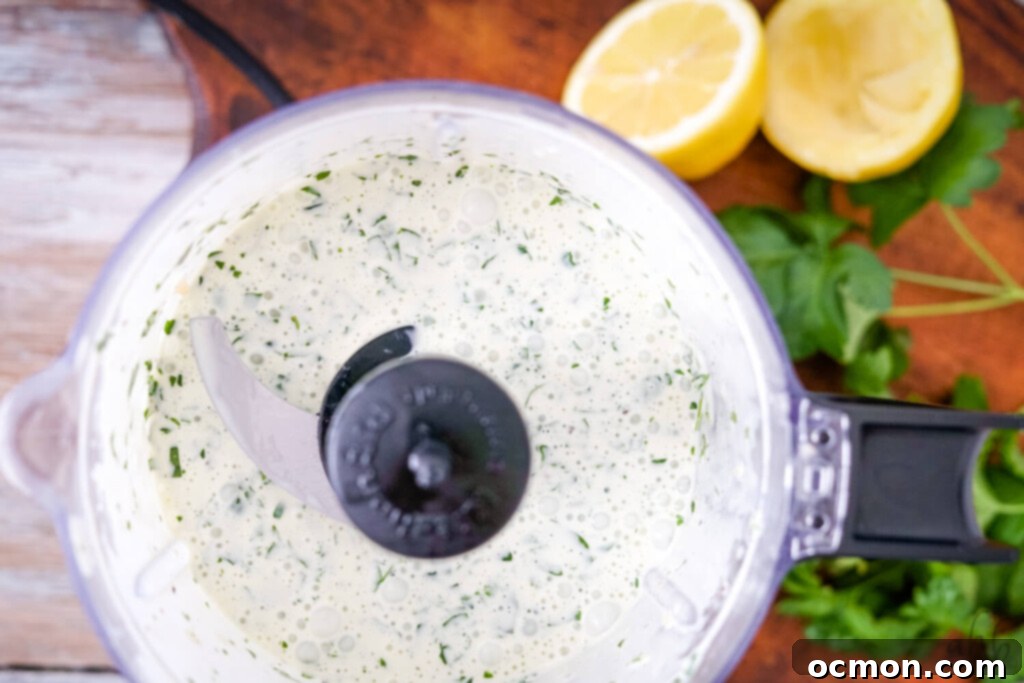 The smooth, blended creamy herbed lemon dressing in a food processor, ready to be added to the tuna salad.