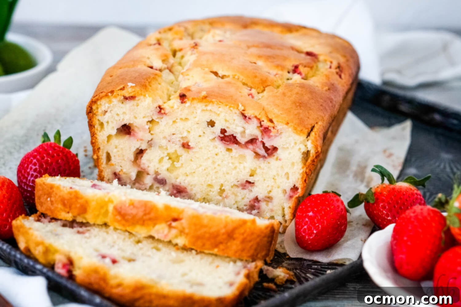 A sliced loaf of Strawberry Bread on a tray with fresh strawberries on each side.