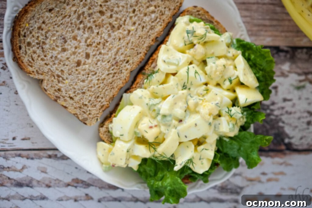 Grandma's Classic Egg Salad 4 An appetizing open-face egg salad sandwich generously spread on toast, presented on a clean white plate. A delightful presentation for a quick meal.