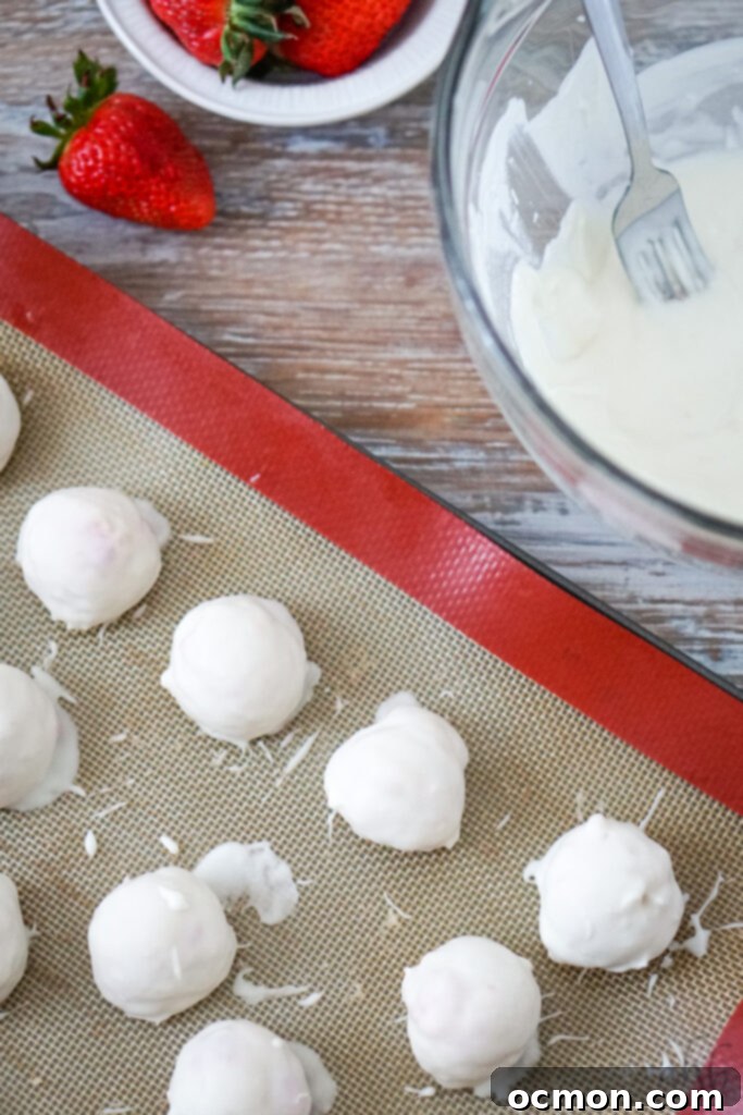 A plate of strawberry cheesecake truffles, some dusted with powdered sugar, others plain, arranged artfully.
