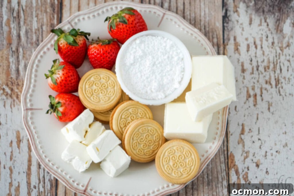 All the ingredients for strawberry cheesecake truffles laid out: vanilla cookies, fresh strawberries, cream cheese, powdered sugar, and almond bark.