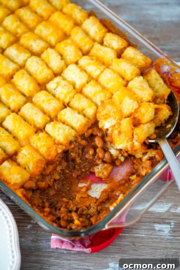 Hearty Pulled Pork Tater Tot Bake 2 A close-up shot of a Pulled Pork Tater Tot Casserole, showcasing the golden tater tots on top and a serving spoon scooping out a portion.