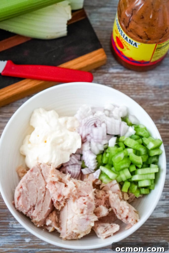 Tangy Buffalo Tuna Twist 5 All the ingredients for Buffalo Tuna Salad laid out on a cutting board, including tuna, celery, shallots, mayo, and hot sauce.