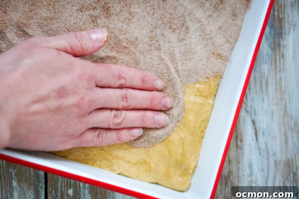 Cinnamon Sugar Churro Bars 7 Sprinkling cinnamon sugar over the churro bar dough in the baking pan.