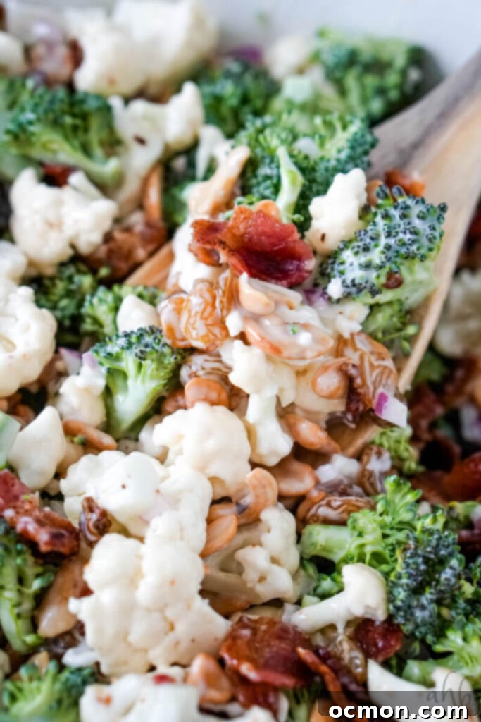 Amish-Style Creamy Broccoli and Cauliflower Salad 2 A spoonful of creamy Amish Broccoli Cauliflower salad, highlighting its rich texture and colorful ingredients.